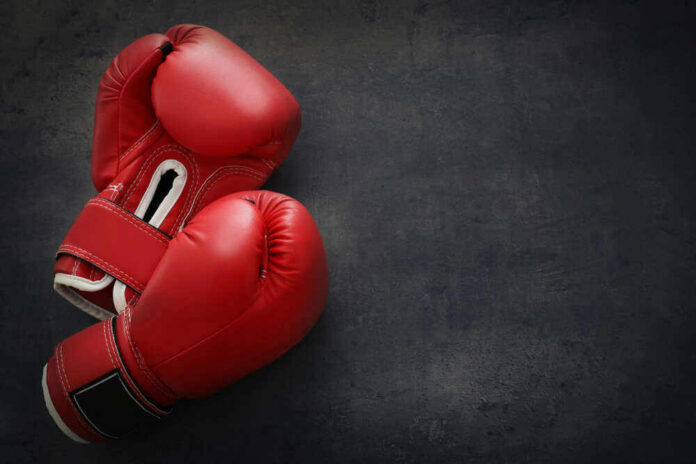 Red boxing gloves on a dark, textured surface.