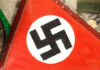Nazi Shrine Flip: Police Move In Close-up of a red flag featuring a black swastika symbol