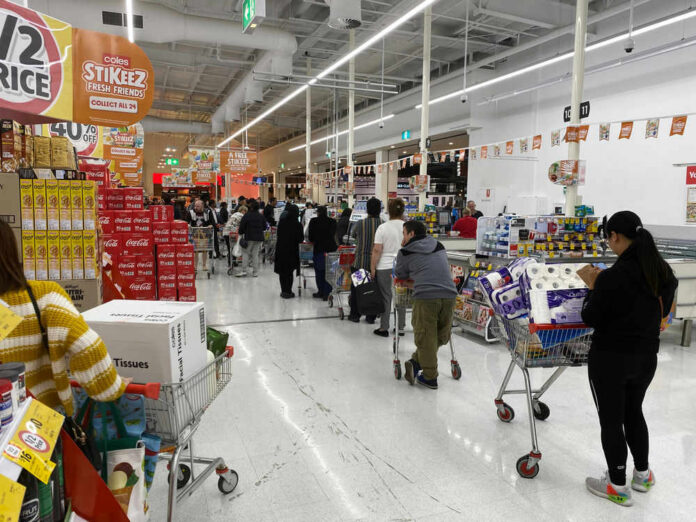 Customers waiting in line at a supermarket checkout.