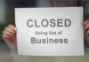 Pizza Giant Axed — Dozens Go Dark A person holding a sign that reads 'CLOSED Going Out of Business'