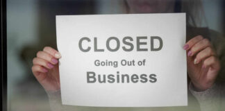 A person holding a sign that reads 'CLOSED Going Out of Business'