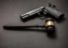 Pistol and judge's gavel on dark surface