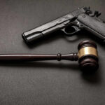 Pistol and judge's gavel on dark surface