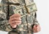 Military personnel holding a bundle of cash