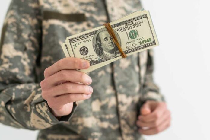Army,Soldier,Holding,Money,Against,White,Background Military personnel holding a bundle of cash