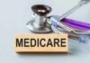Medicare Cushion YANKED — 2027 Shock Brewing? Wooden block with MEDICARE text next to a stethoscope