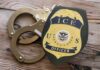 Airport Ambush Stuns Visa Holders ICE officer badge next to handcuffs on a wooden surface