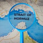 Hormuz Shock Slams Farm Costs Magnifying glass highlighting the Strait of Hormuz on a map