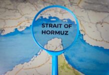 Hormuz Shock Slams Farm Costs Magnifying glass highlighting the Strait of Hormuz on a map