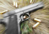 Gunfight Erupts: Deputy Marshal Killed Pistol and bullets on grass with motion blur effect.