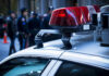 NFL Family Horror Stuns Team Police car lights with officers blurred in background.