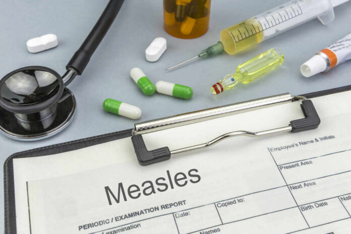 Medical supplies including a stethoscope, syringes, and medication related to measles