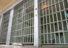 Empty prison cell with metal bars and toilet.