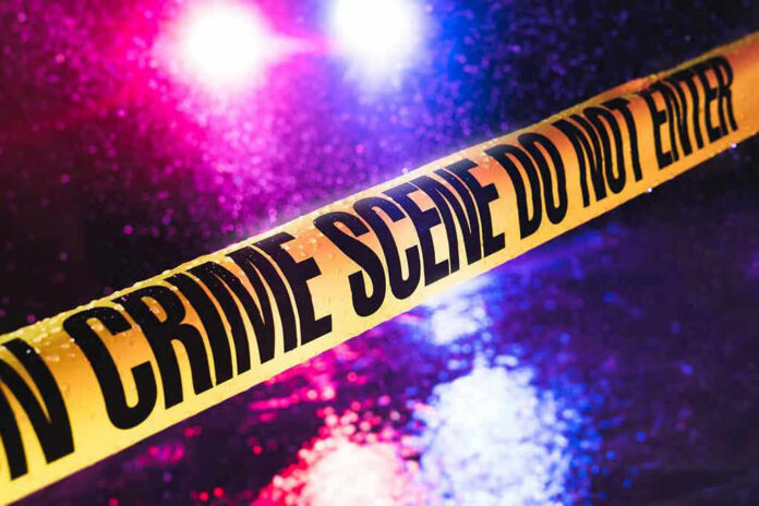 790342249 Crime scene tape with flashing lights in background.