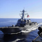 U.S. Warship Blasts Narco Boat Warship with American flag sailing in the ocean.