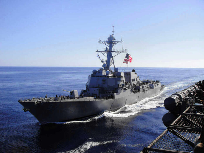 shutterstock_1250591794 Warship with American flag sailing in the ocean.