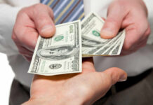 Two hands exchanging cash bills