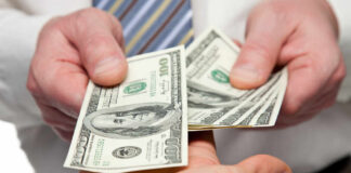 Two hands exchanging cash bills