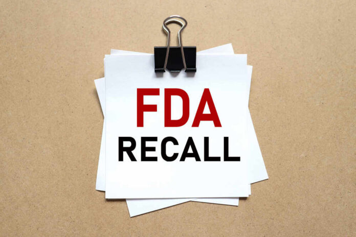 Fda,Recall.,The,Paper,Is,Clamped,With,A,Clerical,Clip. A notice labeled 'FDA RECALL' clipped to white papers on a brown background