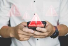 Hands holding a smartphone with warning icons overlay