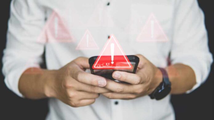 Hands holding a smartphone with warning icons overlay