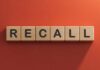 Wooden letter tiles spelling recall on an orange background