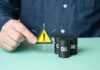 Oil Power Grab Stuns Markets A person holding a warning sign next to oil barrels