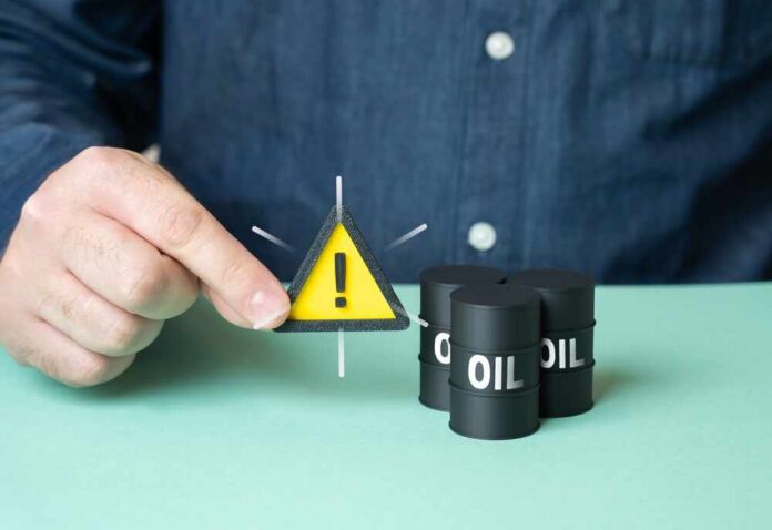 Man,Warns,About,Oil,Supplies.,Fear,Of,Rising,Prices,,Falling A person holding a warning sign next to oil barrels