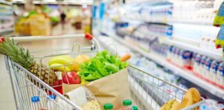 A shopping cart filled with fresh fruits, vegetables, and groceries