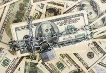385 Trump Accounts Vanish Overnight WHY? A stack of hundred dollar bills secured with a chain and padlock
