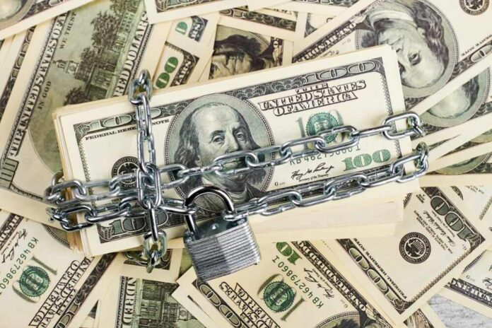 shutterstock_583026472 A stack of hundred dollar bills secured with a chain and padlock