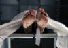 Feet of a covered body on a morgue table with a toe tag