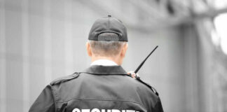 Security guard holding a radio, facing away.