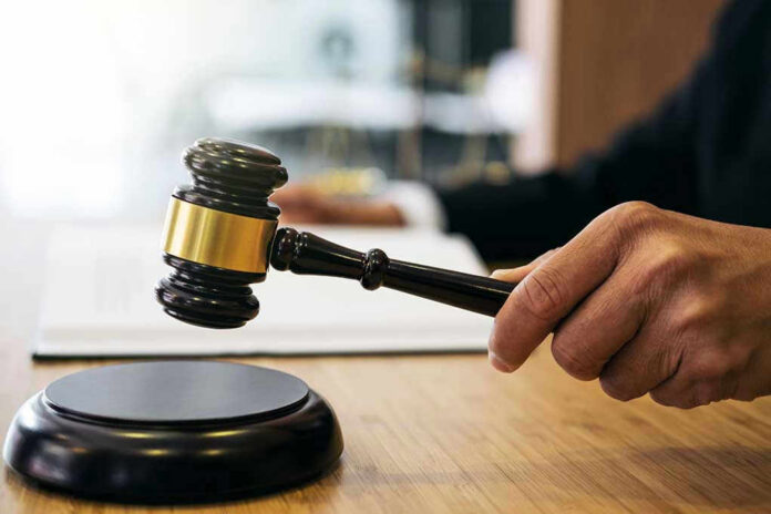1023698749 Gavel in judges hand about to strike.