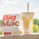 A Big Mac box next to a McDonald's drink cup on a ledge