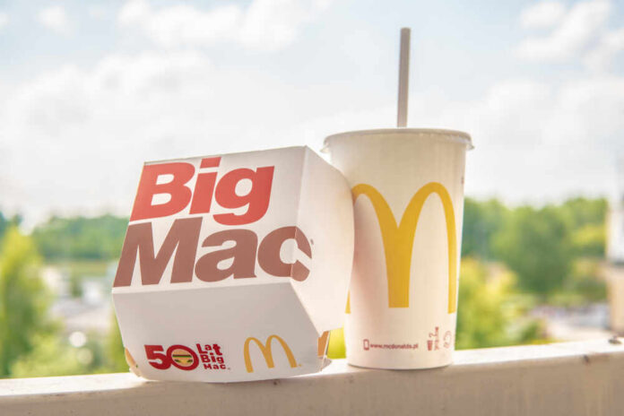 A Big Mac box next to a McDonald's drink cup on a ledge