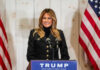 Woman speaking at Trump podium, two American flags present.