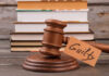 Guilty Murder Plea In Peril? Showdown Set A wooden gavel with a tag reading 'Guilty' next to stacked books