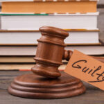 Guilty Murder Plea In Peril? Showdown Set A wooden gavel with a tag reading 'Guilty' next to stacked books
