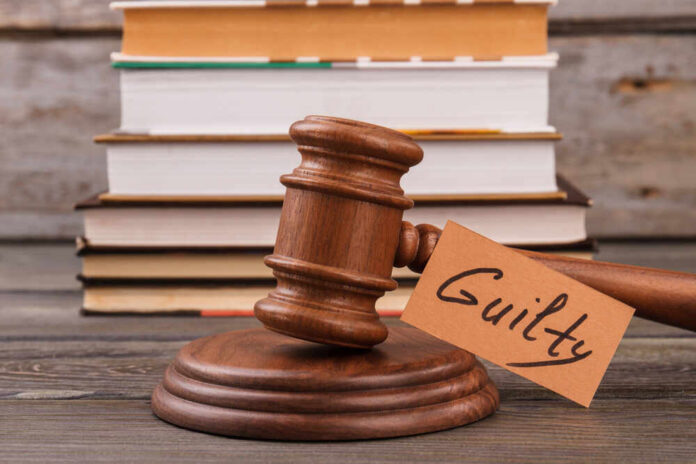 Gulity,Verdict,Concept.,Wooden,Gavel,And,Stack,Of,Books. A wooden gavel with a tag reading 'Guilty' next to stacked books