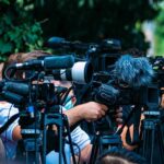 Backroom Revolt Upends GOP’s Safe Seat? TV news cameras crowding together at an outdoor event