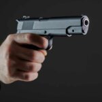 Warnings Ignored — Then A Mass Shooting Hand holding a semi-automatic pistol pointed forward
