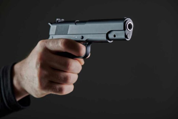 Male,Hand,Holding,A,Gun,On,Black,Background,.,A Hand holding a semi-automatic pistol pointed forward