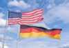 Flags of the United States and Germany waving against a blue sky