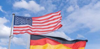 Flags of the United States and Germany waving against a blue sky