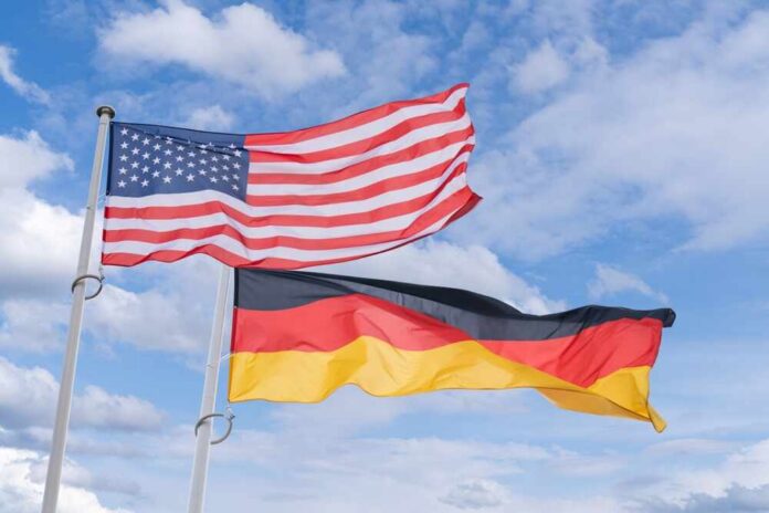 Usa,And,German,Flags,Flutter,In,The,Wind Flags of the United States and Germany waving against a blue sky