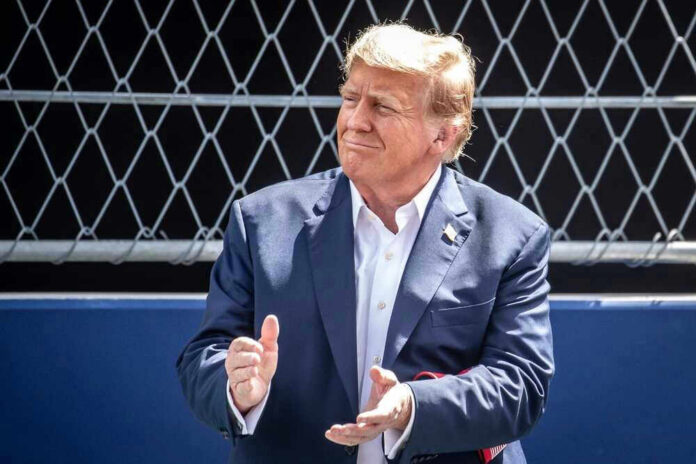 shutterstock_2459917047 Donald Trump clapping, wearing suit.