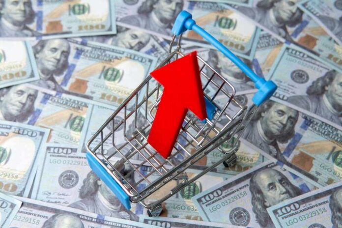 A,Shopping,Cart,And,Red,Upward,Pointing,Arrow,On,A Shopping cart with red upward arrow on US hundred dollar bills