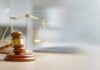 Murder Case CRACKS — Jury Drops Bomb A wooden gavel and scales of justice on a desk