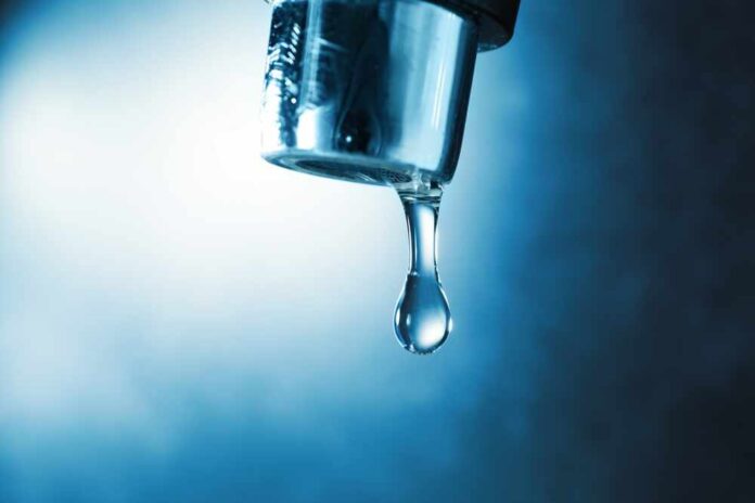 Water,Dripping,Down,From,Faucet,On,Color,Background,,Closeup Water droplet hanging from a metal faucet